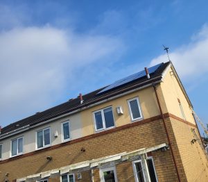 Solar panels installed on a tilted roof, under a blue sky.